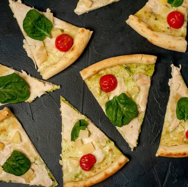 siyah taş arka plan üzerinde kiraz domates ve taze ıspanak yaprakları ile pizza
