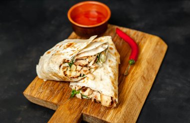 Ahşap doğrama tahtası üzerinde baharatlı sos ile tavuk ve sebze ile sarılmış geleneksel Meksika burrito 