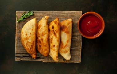 Ahşap doğrama tahtası üzerinde domates soslu Geleneksel Latin Amerika kızarmış empanadas 