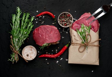 Çiğ taze biftek siyah taş arka plan üzerinde baharat ile kağıt sarılmış 