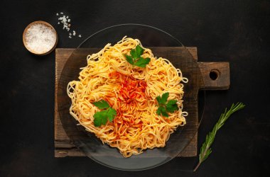 koyu taş arka plan üzerinde domates sosu ve maydanoz yaprakları ile İtalyan spagetti makarna