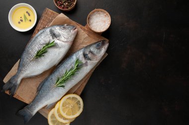 Ahşap doğrama tahtası üzerinde limon dilimleri ve biberiye dalları ile çiğ balık