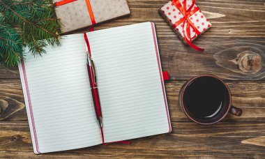 Eski ahşap arka plan üzerinde kırmızı yay ve boş defter ile hediye kutuları yığını 