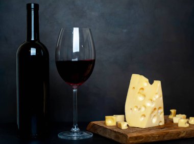 Ahşap tahta üzerinde Maasdam peynirsiyah taş arka plan üzerinde kırmızı şarap ile servis 