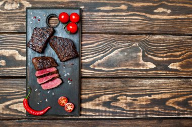 kahverengi ahşap masa üzerinde ahşap tahta üzerinde kiraz domates ve biber ile taze ızgara sığır biftek