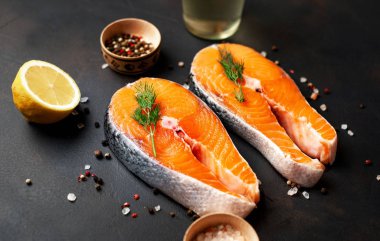 Siyah taş arka plan üzerinde baharat ve limon ile taze çiğ somon biftek