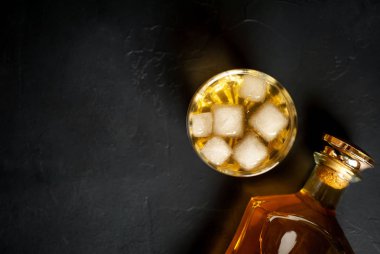 Siyah arka planda buz küpleri ve viski şişesi ile viski Bir bardak 