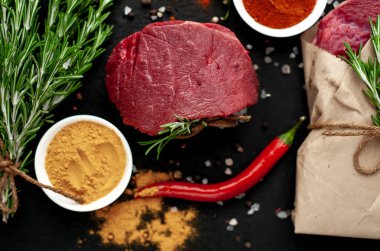 Siyah taş arka planda renkli baharatlar ile Çiğ biftek