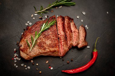 Siyah taş arka plan üzerinde baharat ve biberiye dalları ile Taze ızgara domuz biftek