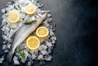 Soğuk ezilmiş buz yığını üzerinde limon dilimleri ve biberiye ile taze balık yakın görünümü