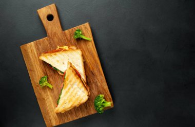 Ahşap doğrama tahtasında jambon, taze brokoli ve peynirile taze ızgara sandviçler