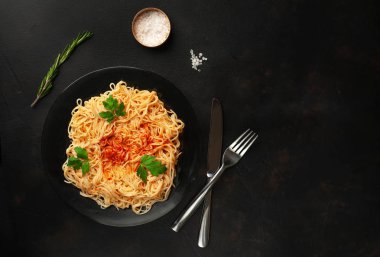 koyu taş arka plan üzerinde domates sosu ve maydanoz yaprakları ile İtalyan spagetti makarna