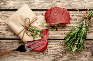 Ahşap arka plan üzerinde zanaat kağıt sarılmış baharat ile Çiğ biftek 