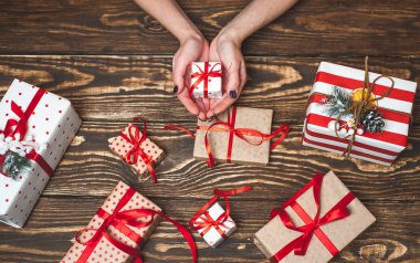 Eski ahşap arka plan üzerinde kırmızı yay ile kadın elleri dekorasyon hediye kutuları 