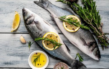 Gri ahşap arka plan üzerinde limon dilimleri ve biberiye dalları ile çiğ balık