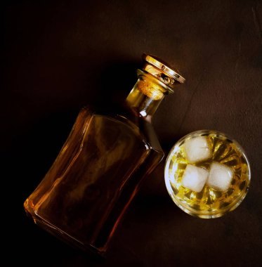 Siyah arka planda buz küpleri ve viski şişesi ile viski Bir bardak 