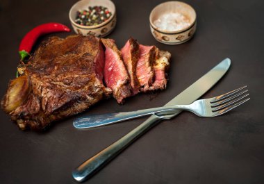 Siyah taş arka plan üzerinde baharat ve biber ile Yağlı ızgara domuz biftek