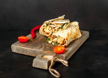 Geleneksel Meksika burrito tavuk ve sebze ile sarılmış ahşap doğrama tahtası üzerinde olgun domates ile servis 