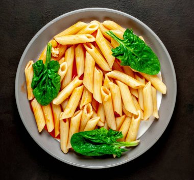 taş siyah arka plan üzerinde yeşil yaprakları ile servis domates soslu makarna