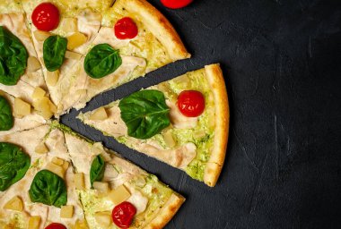 siyah taş arka plan üzerinde kiraz domates ve taze ıspanak yaprakları ile pizza