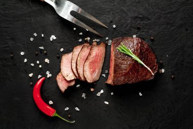 Siyah taş arka plan üzerinde baharat ve biberiye dal ile Taze ızgara biftek