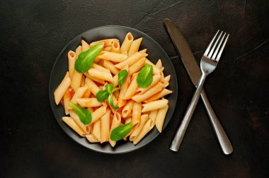 taş siyah arka plan üzerinde yeşil yaprakları ile servis domates soslu makarna