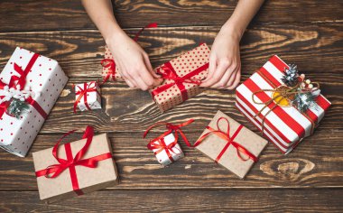 Eski ahşap arka plan üzerinde kırmızı yay ile kadın elleri dekorasyon hediye kutuları 