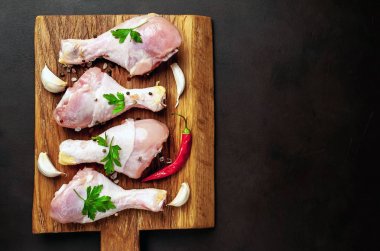 Ahşap doğrama tahtası üzerinde baharat, biber ve sarımsak ile Tavuk bacakları 