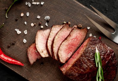 Siyah taş arka plan üzerinde baharat ve biberiye dal ile Taze ızgara biftek