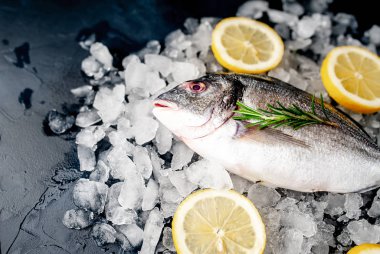 Soğuk ezilmiş buz yığını üzerinde limon dilimleri ve biberiye ile taze balık yakın görünümü