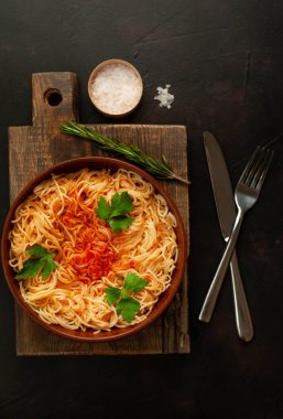 koyu taş arka plan üzerinde domates sosu ve maydanoz yaprakları ile İtalyan spagetti makarna