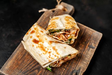 Ahşap doğrama tahtası üzerinde tavuk ve sebze ile sarılmış ev yapımı Meksika burrito 
