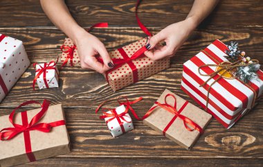 Eski ahşap arka plan üzerinde kırmızı yay ile kadın elleri dekorasyon hediye kutuları 