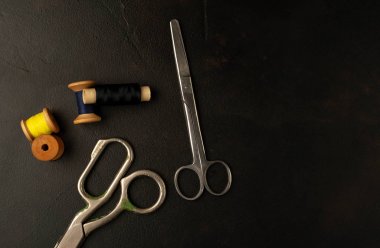siyah arka plan üzerinde dikiş makaraları yığını ile terzi makasları 