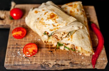 Geleneksel Meksika burrito tavuk ve sebze ile sarılmış ahşap doğrama tahtası üzerinde olgun domates ile servis 