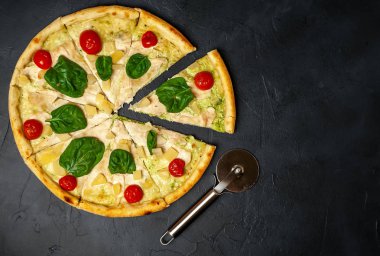 siyah taş arka plan üzerinde kiraz domates ve taze ıspanak yaprakları ile pizza