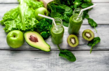 Gri arka planda sebze ve meyve ile Taze yeşil smoothie