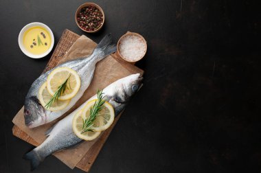 Ahşap doğrama tahtası üzerinde limon dilimleri ve biberiye dalları ile çiğ balık