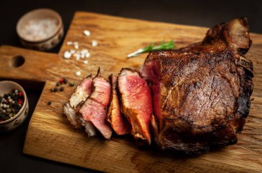 Siyah taş arka plan üzerinde ahşap doğrama tahtası üzerinde baharat ile Yağlı ızgara domuz biftek