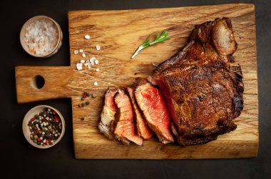 Siyah taş arka plan üzerinde ahşap doğrama tahtası üzerinde baharat ile Yağlı ızgara domuz biftek