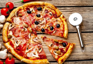 Ahşap arka plan üzerinde mantar, domates, zeytin ve jambon ile taze ev yapımı pizza