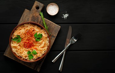 koyu taş arka plan üzerinde domates sosu ve maydanoz yaprakları ile İtalyan spagetti makarna