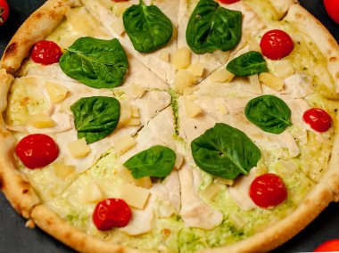 siyah taş arka plan üzerinde kiraz domates ve taze ıspanak yaprakları ile pizza