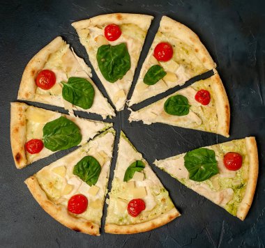 siyah taş arka plan üzerinde kiraz domates ve taze ıspanak yaprakları ile pizza