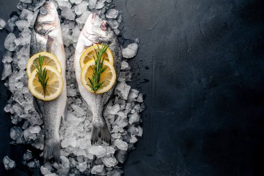 Soğuk ezilmiş buz yığını üzerinde limon dilimleri ve biberiye ile taze balık yakın görünümü