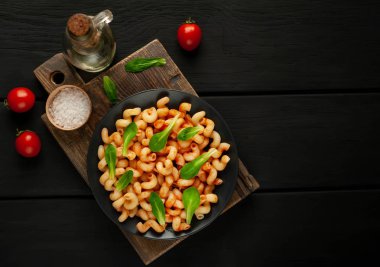 taş siyah arka plan üzerinde ahşap doğrama tahtası üzerinde domates soslu makarna