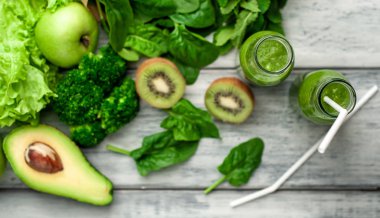 Gri arka planda sebze ve meyve ile Taze yeşil smoothie