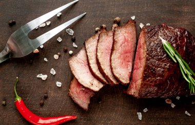 Siyah taş arka plan üzerinde baharat ve biberiye dal ile Taze ızgara biftek