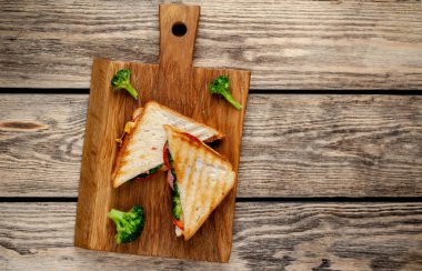 Ahşap doğrama tahtasında jambon, taze brokoli ve peynirile taze ızgara sandviçler