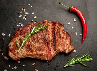 Siyah taş arka plan üzerinde baharat ve biberiye dalları ile Taze ızgara domuz biftek